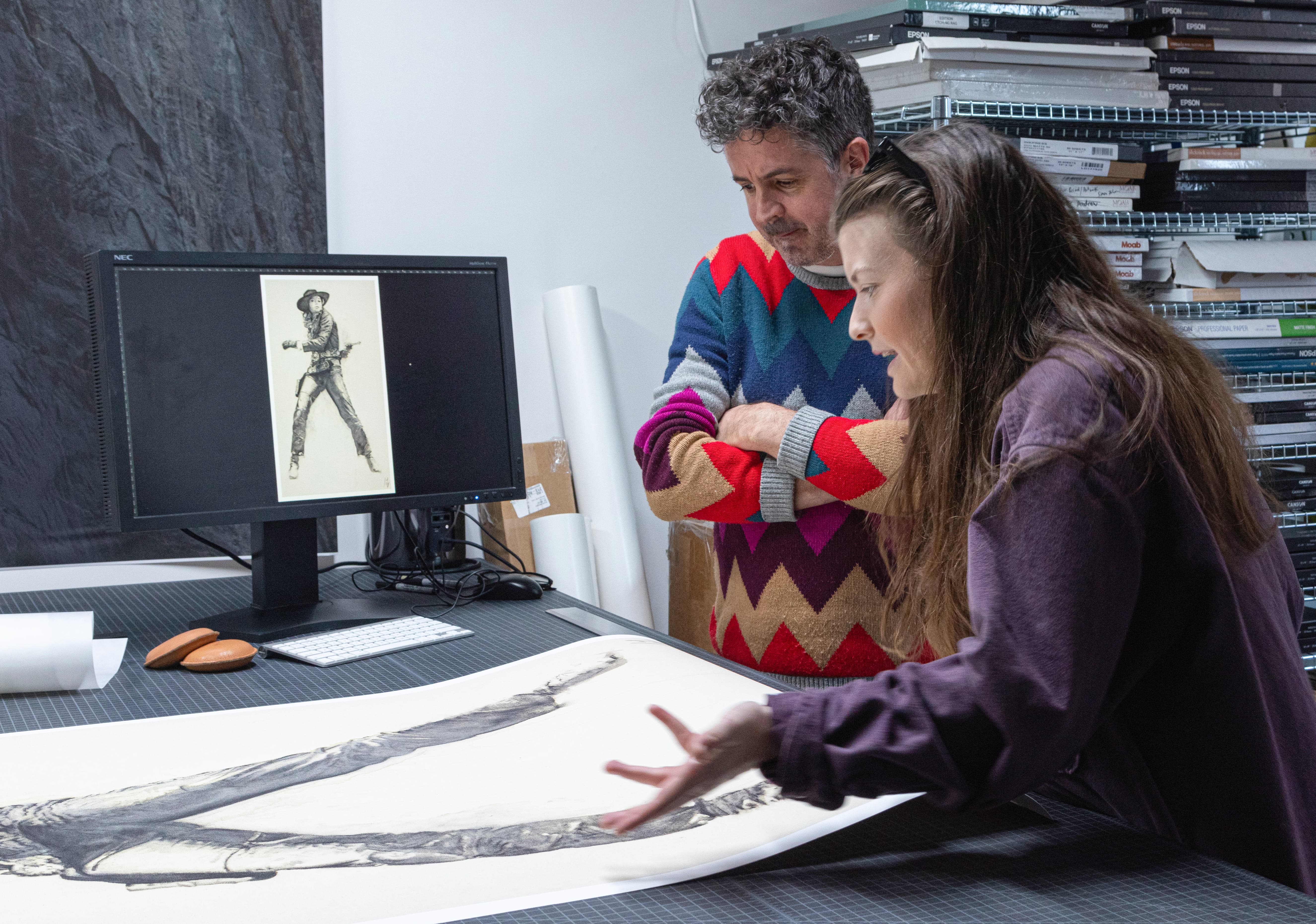 Photograph of Rob MacInnis and Lily Swab discussing her large print edition in front a comparison image